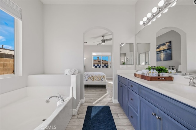 bathroom with wood finish floors, double vanity, ceiling fan, a garden tub, and connected bathroom