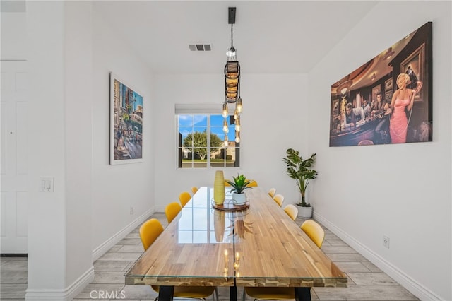 dining room featuring wood finished floors, visible vents, and baseboards