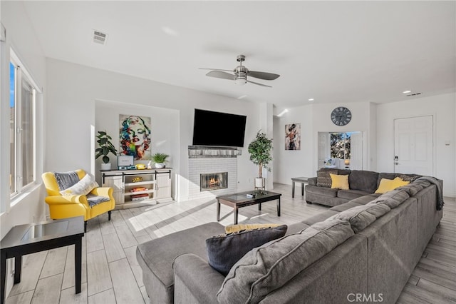 living room with visible vents, a brick fireplace, a ceiling fan, and wood tiled floor