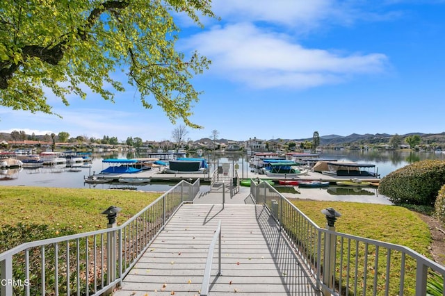 dock area with a water and mountain view and a lawn