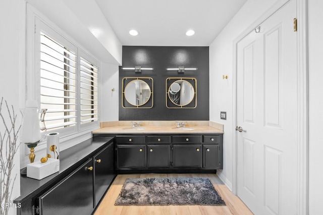 full bath featuring double vanity, recessed lighting, wood finished floors, and a sink