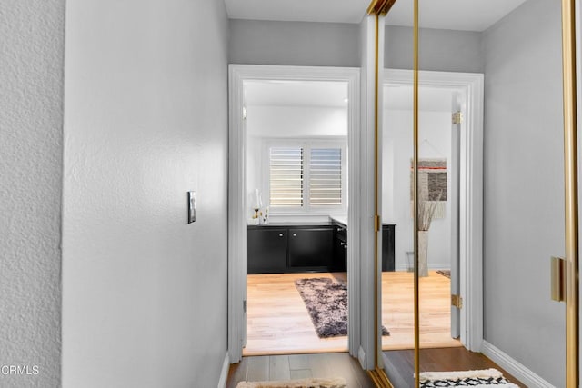 hall with baseboards and wood finished floors