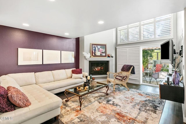 living area featuring recessed lighting, wood finished floors, and a warm lit fireplace