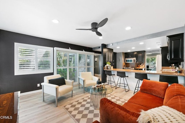 living area featuring recessed lighting, a ceiling fan, light wood-type flooring, and baseboards