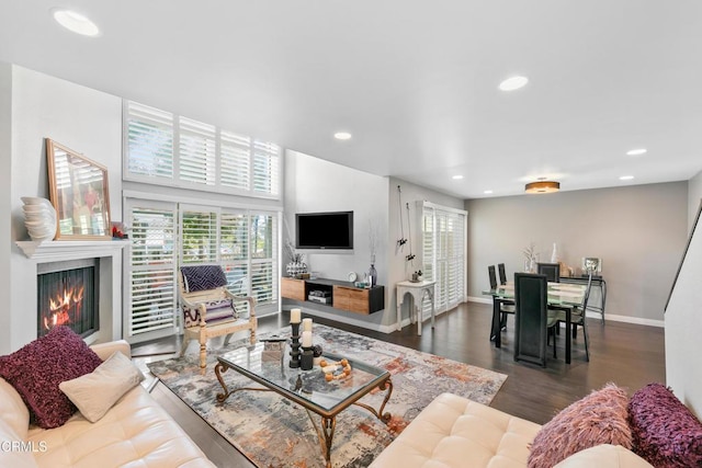 living area with dark wood-style floors, plenty of natural light, recessed lighting, and a lit fireplace