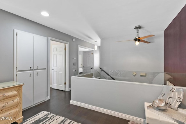 interior space with baseboards, white cabinetry, a ceiling fan, and dark wood-style flooring