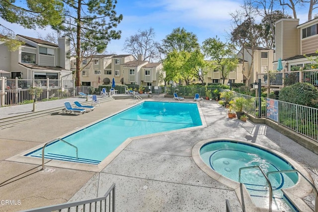 pool featuring a residential view, a hot tub, a patio, and fence