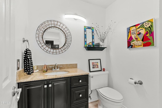 half bath featuring toilet, vanity, and baseboards