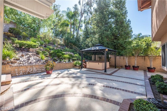 view of patio / terrace featuring a gazebo, a hot tub, and fence