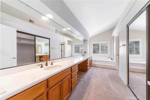 full bath with a garden tub, vanity, and vaulted ceiling