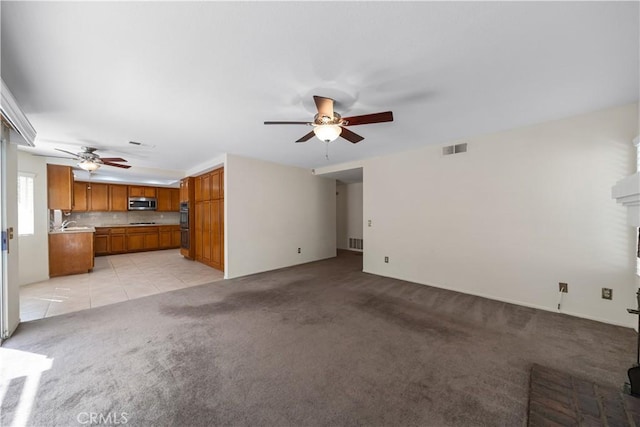 unfurnished living room with light tile patterned floors, a ceiling fan, visible vents, a fireplace, and light carpet