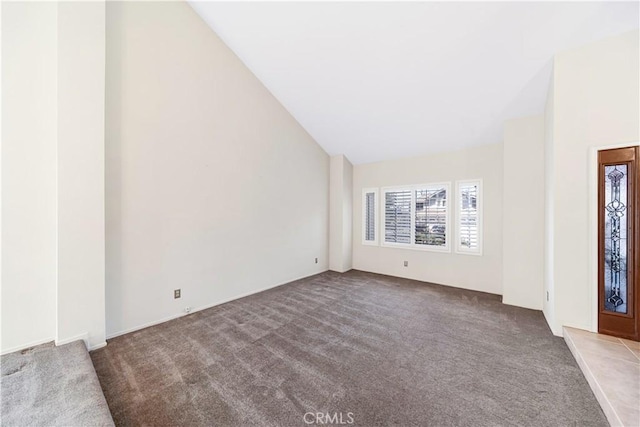 carpeted entrance foyer with high vaulted ceiling