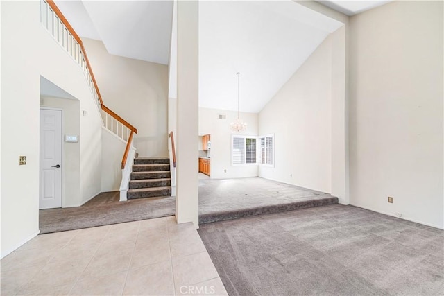 tiled foyer entrance with a notable chandelier, carpet floors, high vaulted ceiling, and stairs