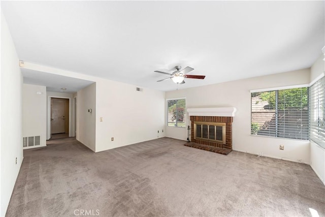 unfurnished living room featuring a ceiling fan, a brick fireplace, carpet, and visible vents