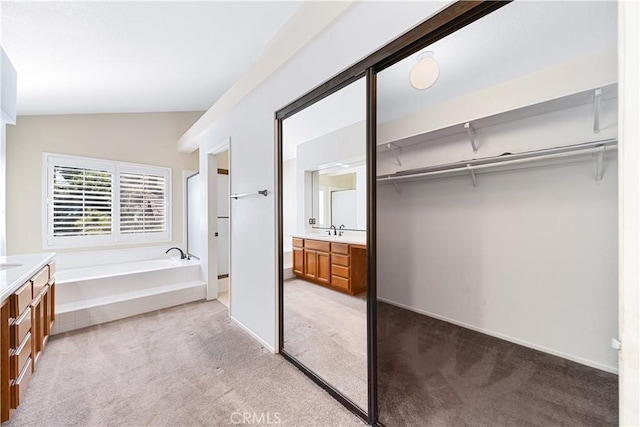 bathroom with vanity, lofted ceiling, a bath, and carpet floors