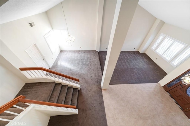 staircase with tile patterned floors, visible vents, a notable chandelier, and high vaulted ceiling