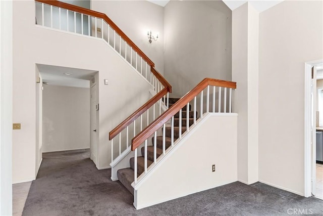 stairway with carpet and a high ceiling