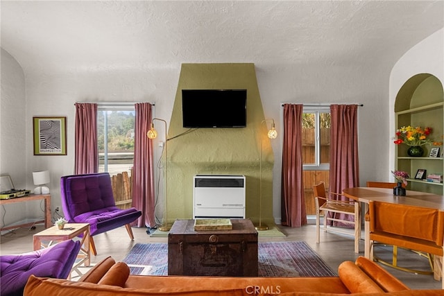 living room featuring heating unit, built in shelves, and a textured ceiling