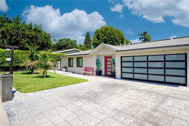 view of front of house with decorative driveway, a garage, a front yard, and stucco siding