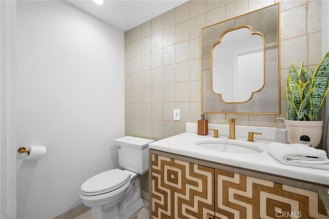 half bath with vanity, tile walls, and toilet