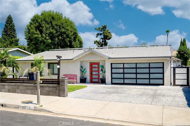 view of front facade with decorative driveway, a garage, a fenced front yard, and stucco siding