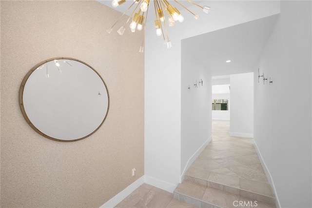 corridor with baseboards and a chandelier