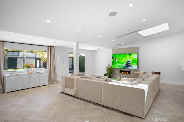 living area with recessed lighting, baseboards, vaulted ceiling with skylight, and a lit fireplace