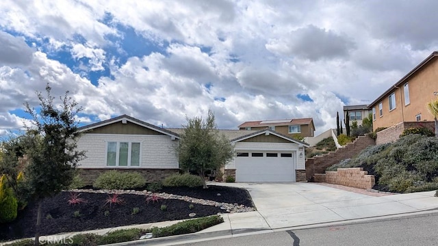 view of front of home with stone siding, an attached garage, and driveway