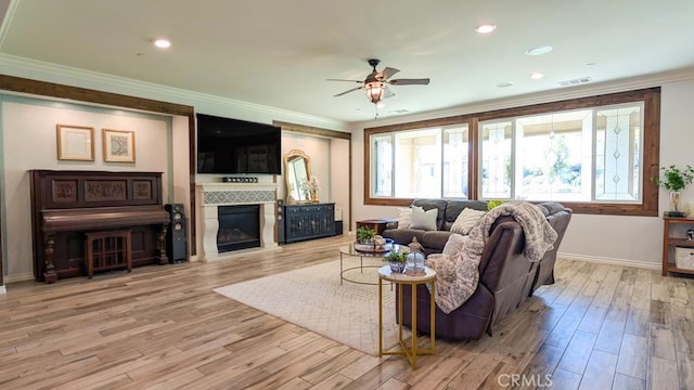 living area featuring visible vents, baseboards, ornamental molding, wood finished floors, and a glass covered fireplace