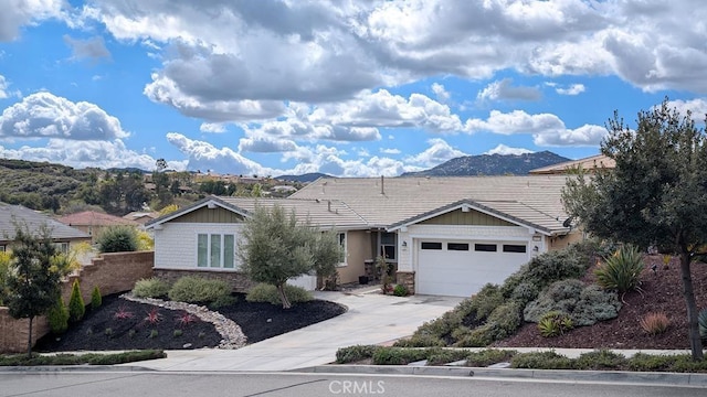 ranch-style house with a garage, stone siding, concrete driveway, and a tile roof