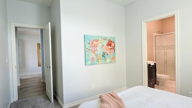 bedroom with connected bathroom and baseboards