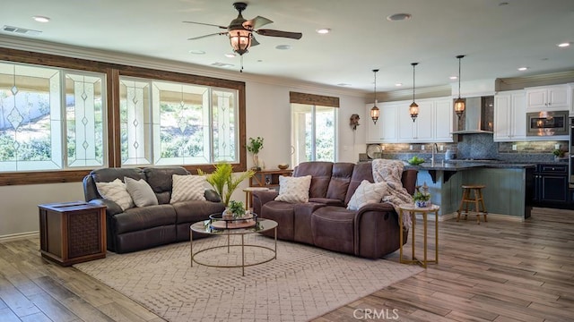 living area with visible vents, crown molding, and wood finished floors