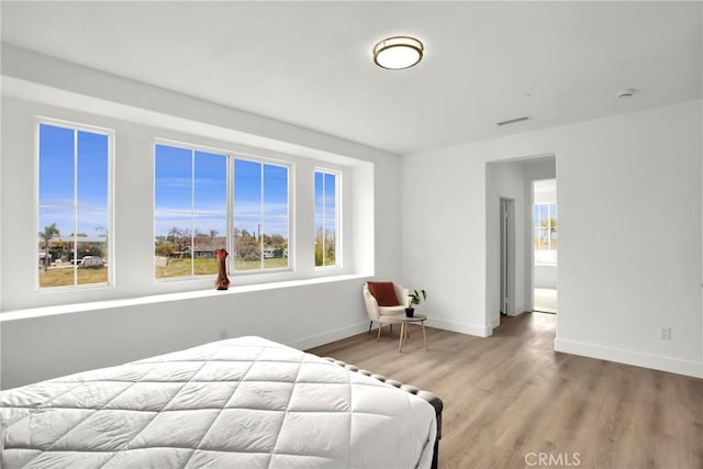 bedroom featuring visible vents, baseboards, and wood finished floors