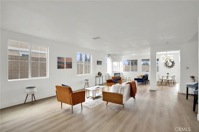 living room with an inviting chandelier, wood finished floors, baseboards, and visible vents