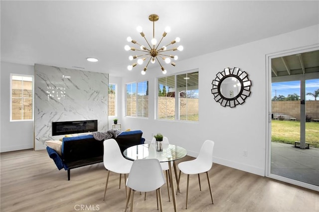 dining room featuring a healthy amount of sunlight, light wood-style flooring, and a high end fireplace