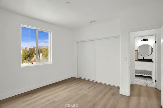 unfurnished bedroom featuring light wood finished floors, visible vents, a closet, and baseboards