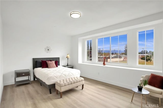 bedroom featuring multiple windows, baseboards, and wood finished floors