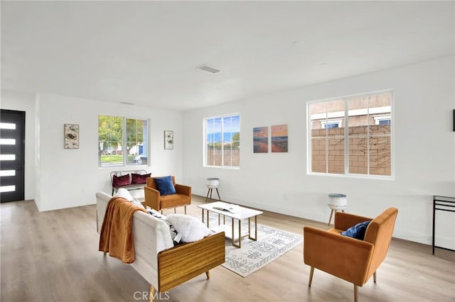 living area with visible vents, plenty of natural light, and wood finished floors