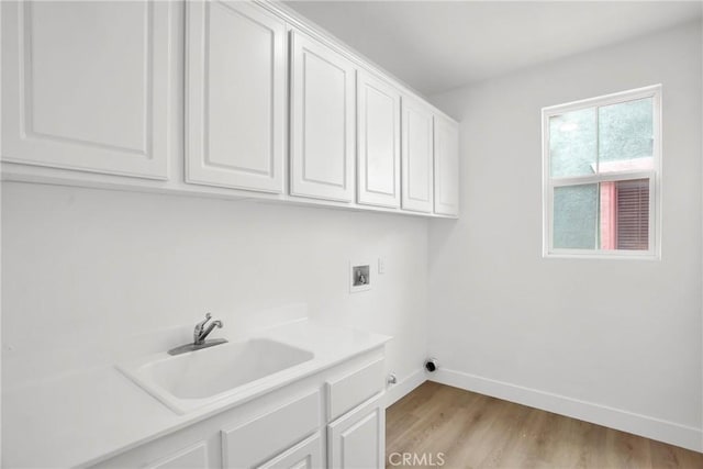 washroom featuring baseboards, cabinet space, a sink, washer hookup, and light wood-style floors