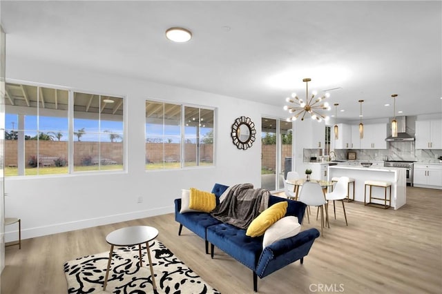 living room featuring baseboards, light wood-style floors, and an inviting chandelier