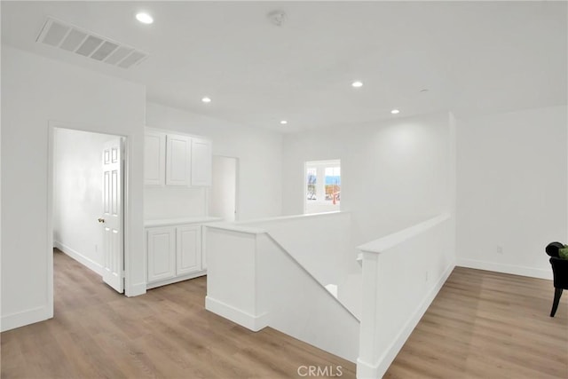 hall with recessed lighting, an upstairs landing, visible vents, and light wood finished floors