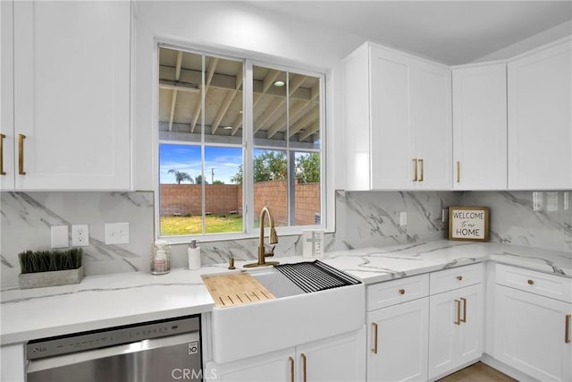 kitchen with dishwasher, light stone counters, white cabinetry, and a sink