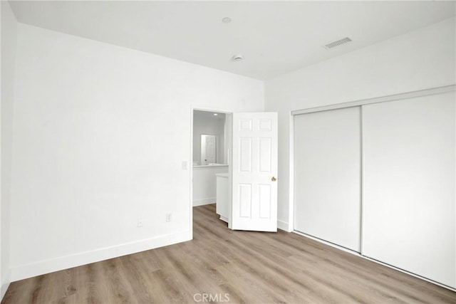 unfurnished bedroom with visible vents, baseboards, a closet, and wood finished floors