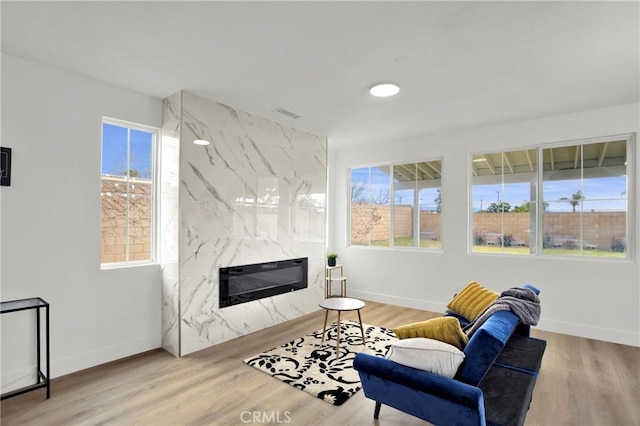 living room with a fireplace, baseboards, and wood finished floors