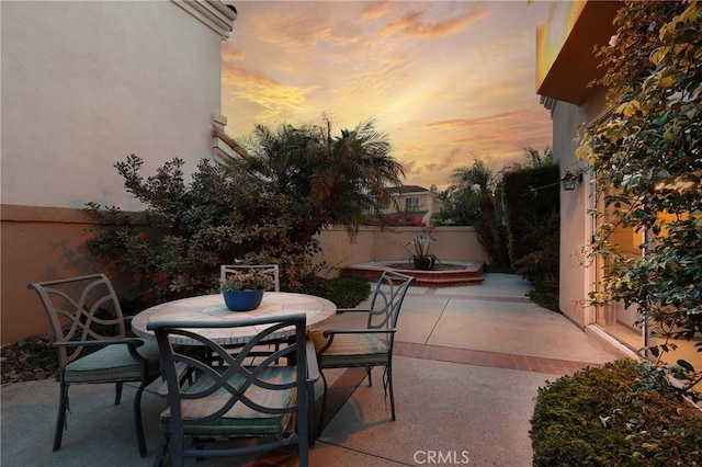 patio terrace at dusk with outdoor dining area and fence