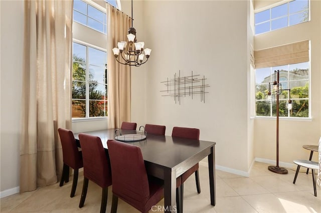 dining room with light tile patterned floors, baseboards, a towering ceiling, and a chandelier