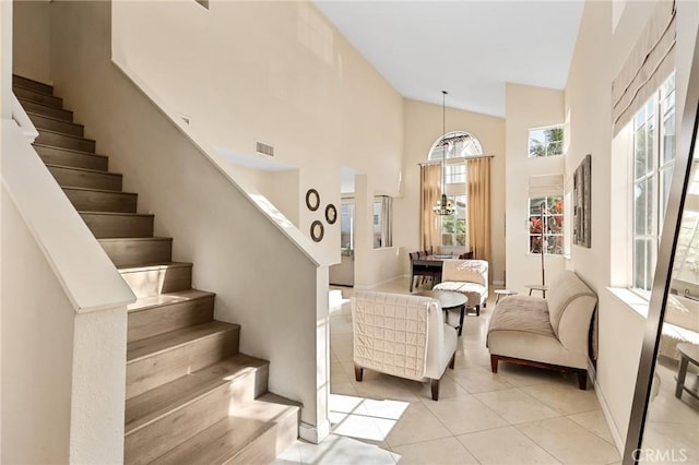 staircase with tile patterned floors, visible vents, and high vaulted ceiling