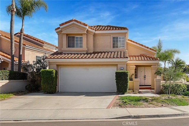 mediterranean / spanish house with concrete driveway, an attached garage, a tile roof, and stucco siding