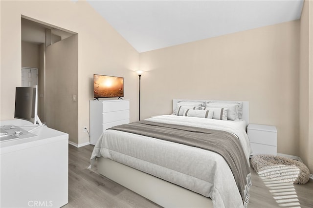 bedroom with vaulted ceiling, wood finished floors, and baseboards