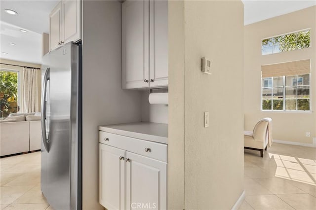 kitchen with freestanding refrigerator, recessed lighting, light countertops, light tile patterned floors, and baseboards